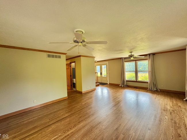 unfurnished living room with a ceiling fan, wood finished floors, ornamental molding, baseboards, and a textured ceiling | Image 48
