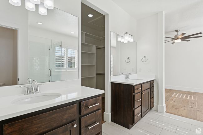 Bathroom featuring a stall shower, two vanities, a ceiling fan, and tile patterned flooring | Image 16