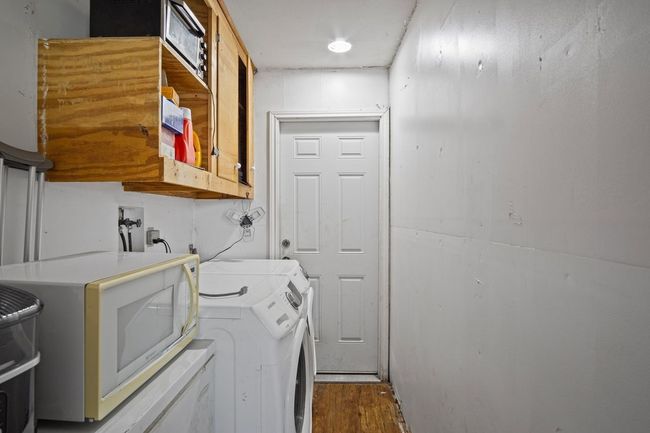 Washroom featuring cabinet space, washing machine and dryer, and dark wood-style flooring | Image 30