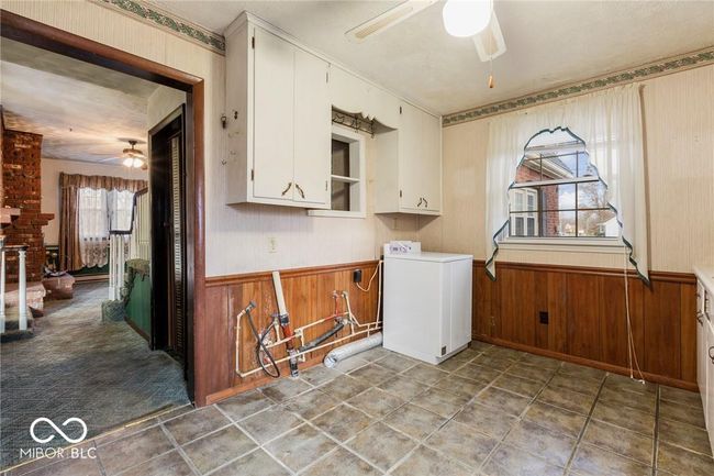 laundry area featuring ceiling fan, washer / clothes dryer, wainscoting, and wood walls | Image 8