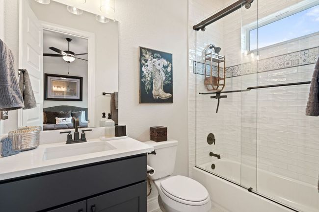 Bathroom with combined bath / shower with glass door, vanity, toilet, and a ceiling fan | Image 26