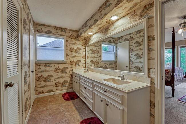 The bathroom also features dual sinks and a spacious vanity with ample counter space and storage. A window brings in natural light, creating a bright and welcoming atmosphere. | Image 22