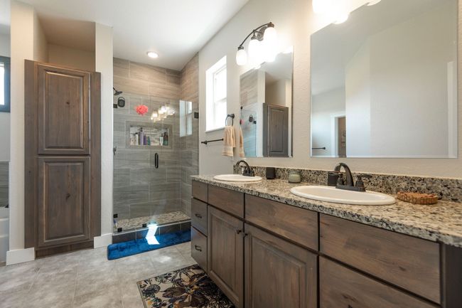 Full bathroom with double vanity, a shower stall, and tile patterned floors | Image 14