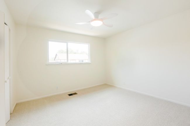 Unfurnished bedroom featuring light colored carpet and a ceiling fan, new windows. | Image 24