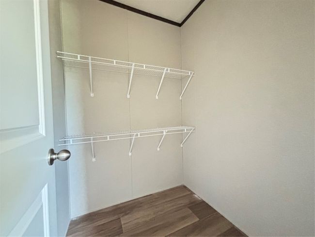 Walk in closet featuring dark wood look finished floors | Image 19