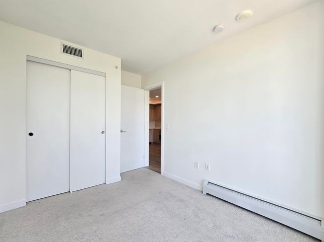 Unfurnished bedroom featuring baseboard heating, carpet, and a closet | Image 10