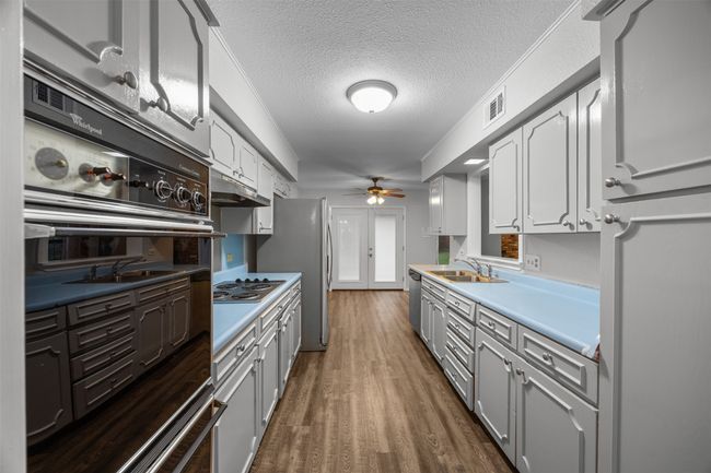 Kitchen with ceiling fan, stainless steel appliances, a sink, wood finished floors, and light countertops | Image 12