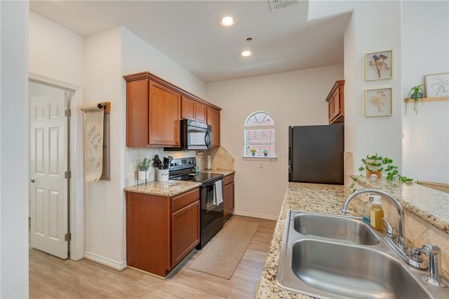 Kitchen featuring black appliances, light wood-style flooring, brown cabinets, recessed lighting, and decorative backsplash | Image 9