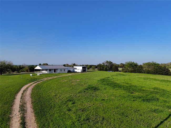 View of green lawn featuring dirt driveway and a rural view | Image 19