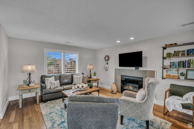 Living room featuring baseboards, a tiled fireplace, wood finished floors, and recessed lighting | Image 7
