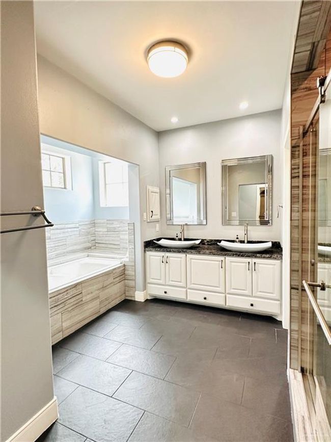 Bathroom featuring a bath, double vanity, a stall shower, tile patterned floors, and recessed lighting | Image 13