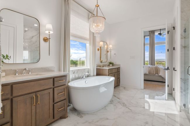 Ensuite bathroom with a marble finish shower, light marble finish flooring, a freestanding tub, two vanities, and a chandelier | Image 24