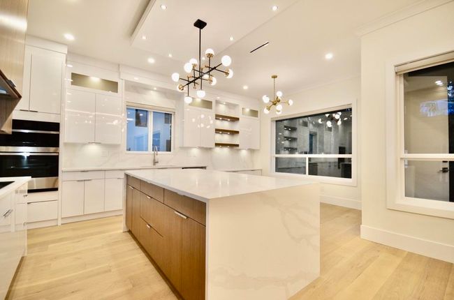 Kitchen featuring modern cabinets, a chandelier, white cabinetry, light wood finished floors, and ornamental molding | Image 8