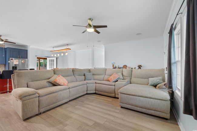 Living room featuring ceiling fan, light wood finished floors, and ornamental molding | Image 8