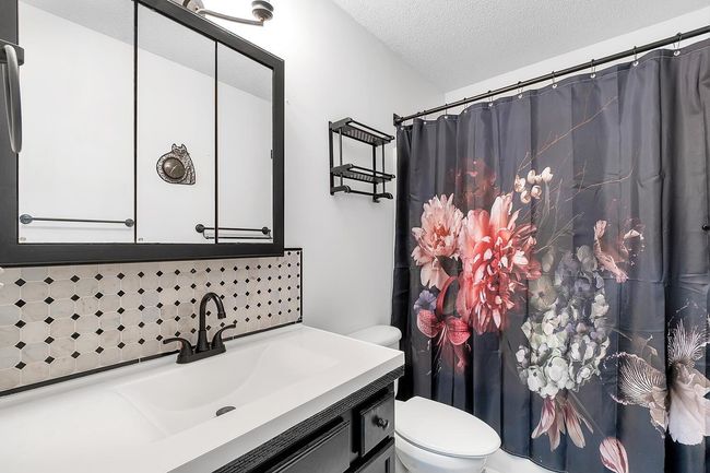 Bathroom with decorative backsplash, vanity, and a tub/shower with shower curtain | Image 18