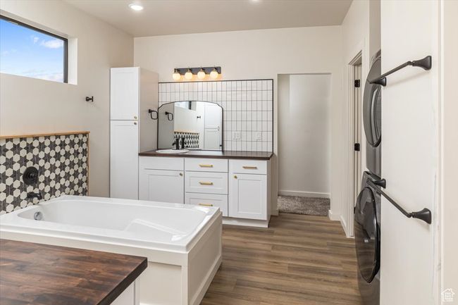 Bathroom featuring hardwood / wood-style floors, vanity, a tub, and stacked washer and clothes dryer | Image 20