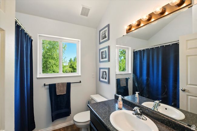Full bath with vaulted ceiling, toilet, vanity, and curtained shower | Image 28