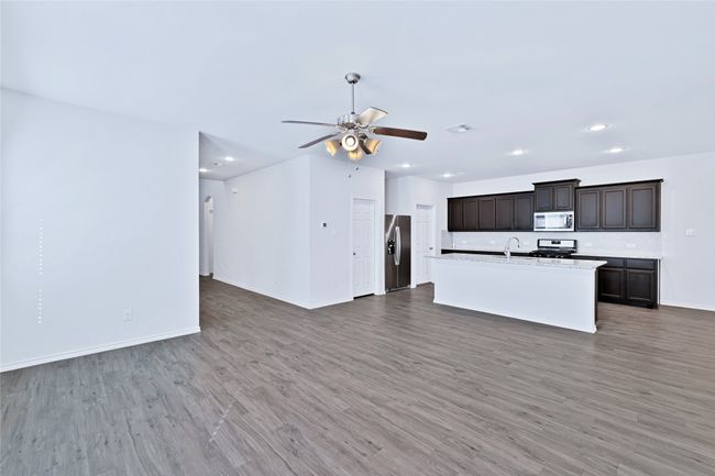 Unfurnished living room with light wood finished floors, ceiling fan, and recessed lighting | Image 5
