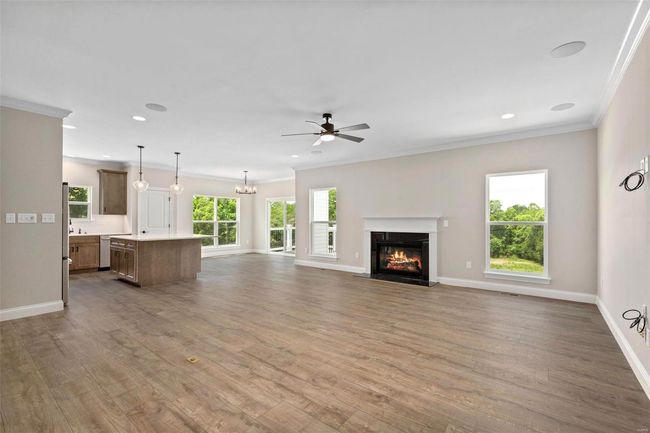 Unfurnished living room with ceiling fan with notable chandelier, wood-type flooring, and ornamental molding | Image 16