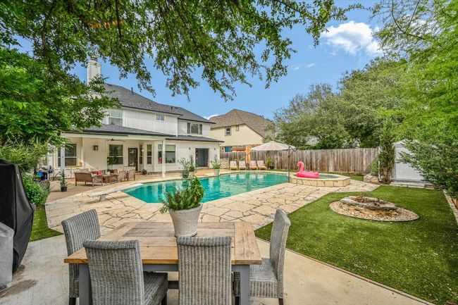 View of swimming pool featuring a patio area, an outdoor living space with a fire pit, ceiling fan, a pool with connected hot tub, and outdoor dining area | Image 30