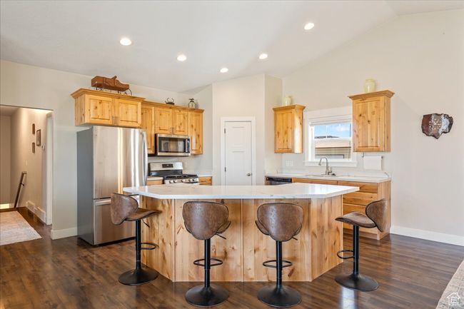 Kitchen featuring lofted ceiling, light countertops, a sink, appliances with stainless steel finishes, and dark wood-style flooring | Image 13