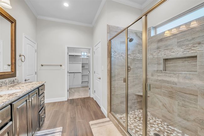 Bathroom featuring vanity, a stall shower, a spacious closet, crown molding, and wood finished floors | Image 20