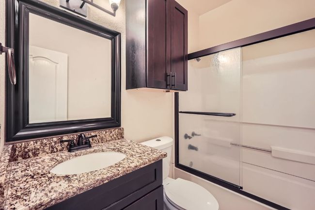 Full bath with toilet, vanity, and combined bath / shower with glass door | Image 16
