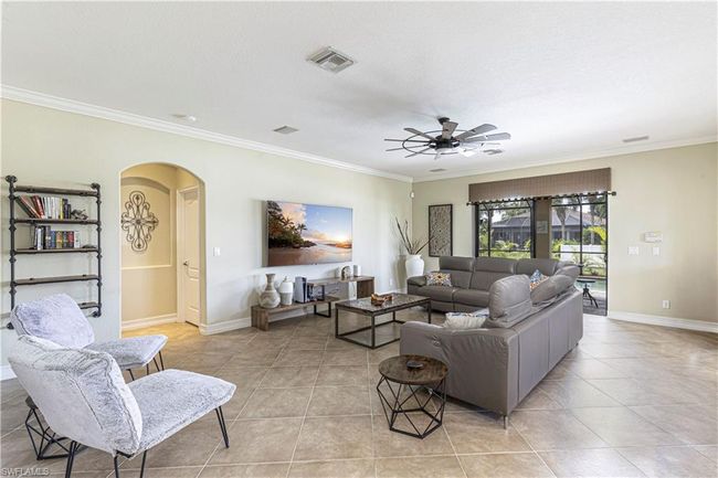 Living room with arched walkways, visible vents, light tile patterned floors, and ornamental molding | Image 6