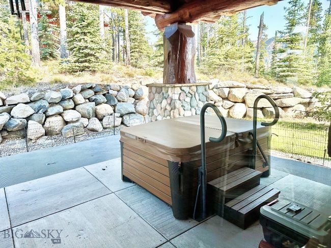 West patio in summer with hot tub and rock retaining wall. | Image 82