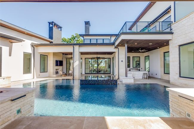 Back of house with a chimney, a ceiling fan, a balcony, a pool with connected hot tub, and a patio | Image 35