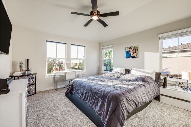 Bedroom featuring light colored carpet, an office area, ceiling fan, and baseboards | Image 19