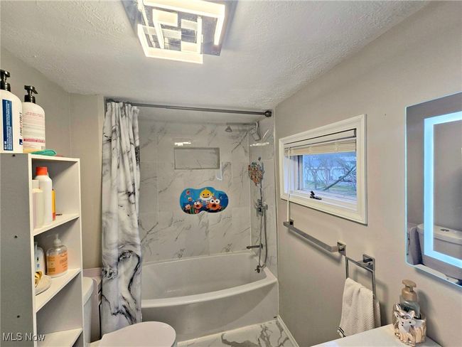 Bathroom featuring toilet, marble finish floor, shower / tub combo, and a textured ceiling | Image 42
