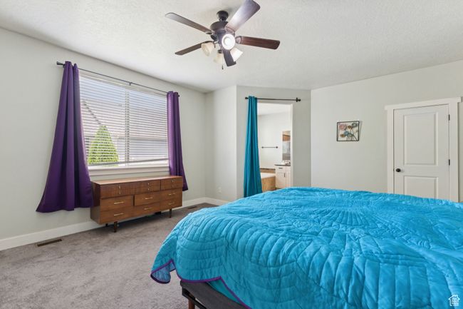 Bedroom featuring carpet floors, baseboards, a textured ceiling, ceiling fan, and connected bathroom | Image 11