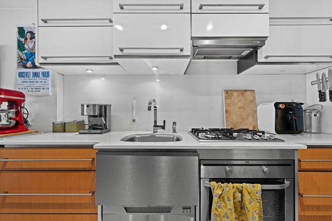 Kitchen with light countertops, brown cabinetry, a sink, and stainless steel appliances | Image 10