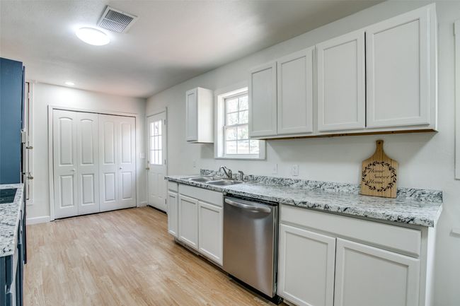 Kitchen featuring dishwasher, light wood-style floors, white cabinets, and light stone counters | Image 10