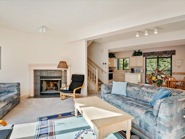 Living area with track lighting, stairway, a tiled fireplace, and light colored carpet | Image 6