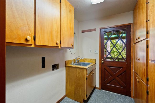 Laundry room has sink and ample cabinetry for storage needs. | Image 32