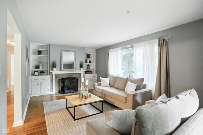 living area with wood finished floors, a fireplace, and built in features | Image 13