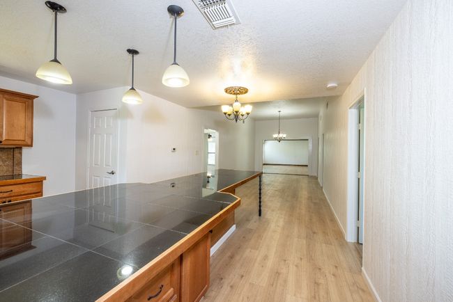 Kitchen featuring an inviting chandelier, visible vents, hanging light fixtures, brown cabinets, and light wood finished floors | Image 8