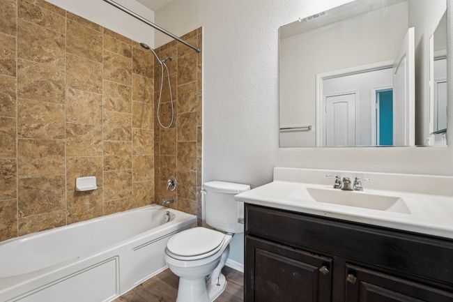 Secondary Bathroom with vanity, toilet, shower / bathtub combination, wood finished floors, and a textured wall | Image 30
