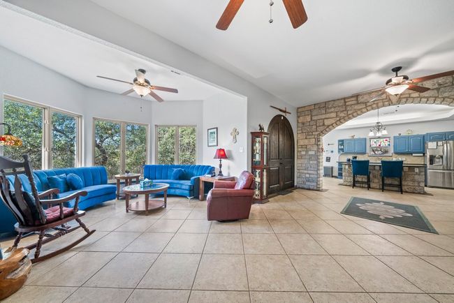 Living room featuring arched walkways, light tile patterned floors, and ceiling fan with notable chandelier | Image 7