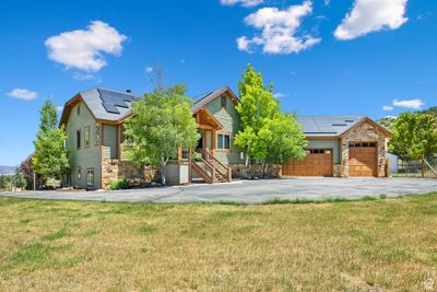 View of front of property featuring a garage, a front lawn, and solar panels | Image 1