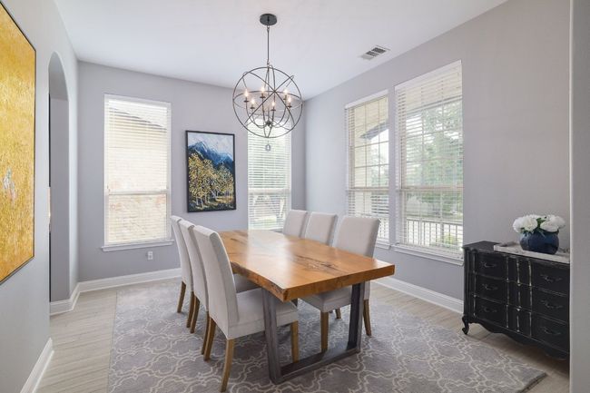 Dining area with baseboards, a chandelier, light wood-style flooring, and arched walkways | Image 12