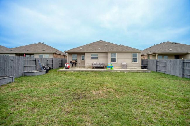 Rear view of house with a fenced backyard, a patio, and a lawn | Image 35