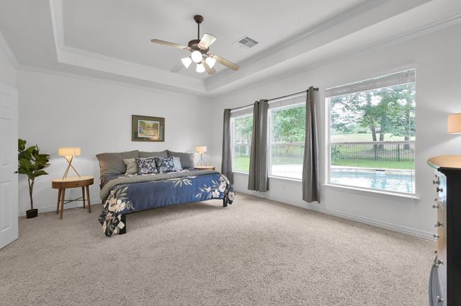 This bright and airy 18 x 14 primary retreat features tray ceilings and a trio of large windows with gorgeous views overlooking the backyard pool and the green on the golf course. | Image 19