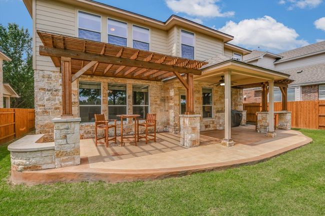 Rear view of house featuring stone siding, a ceiling fan, a patio, and a pergola | Image 29