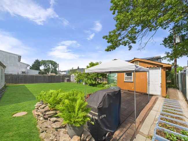 Fenced backyard featuring a storage unit | Image 30