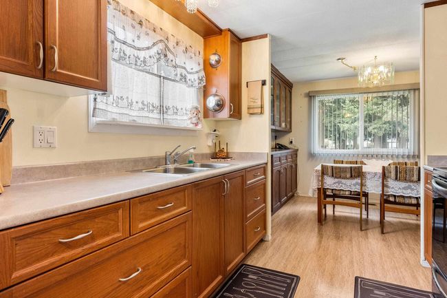 Kitchen with light countertops, a chandelier, a sink, light wood-style floors, and brown cabinetry | Image 15