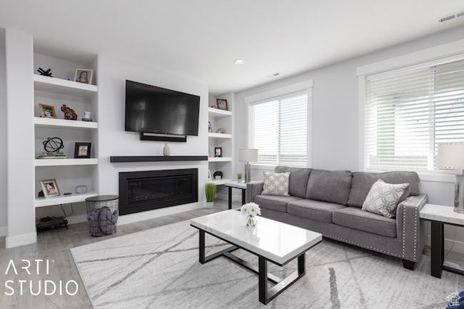 Living room featuring visible vents, a healthy amount of sunlight, a glass covered fireplace, and wood finished floors | Image 18