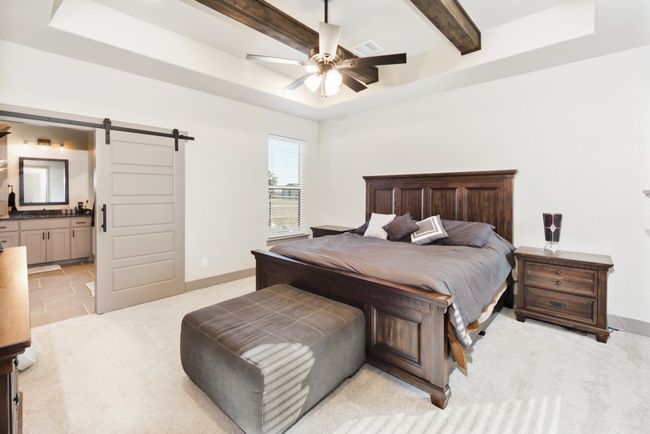 Bedroom featuring connected bathroom, light colored carpet, a barn door, beamed ceiling, and visible vents | Image 22